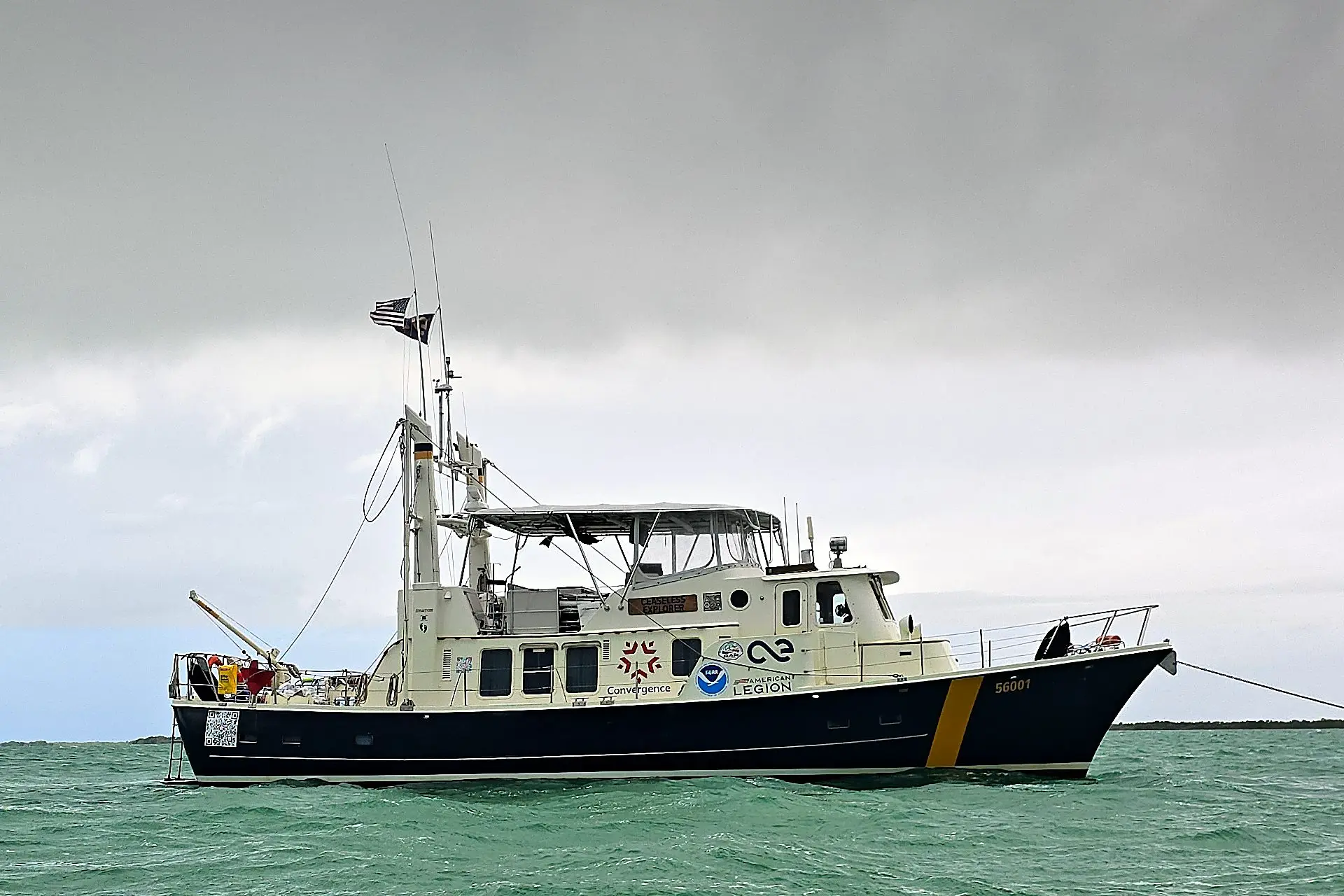 Ceaseless Explorer, our 56-foot expedition trawler, at anchor under stormy skies, with the Convergence, NOAA, and American Legion logos on her side