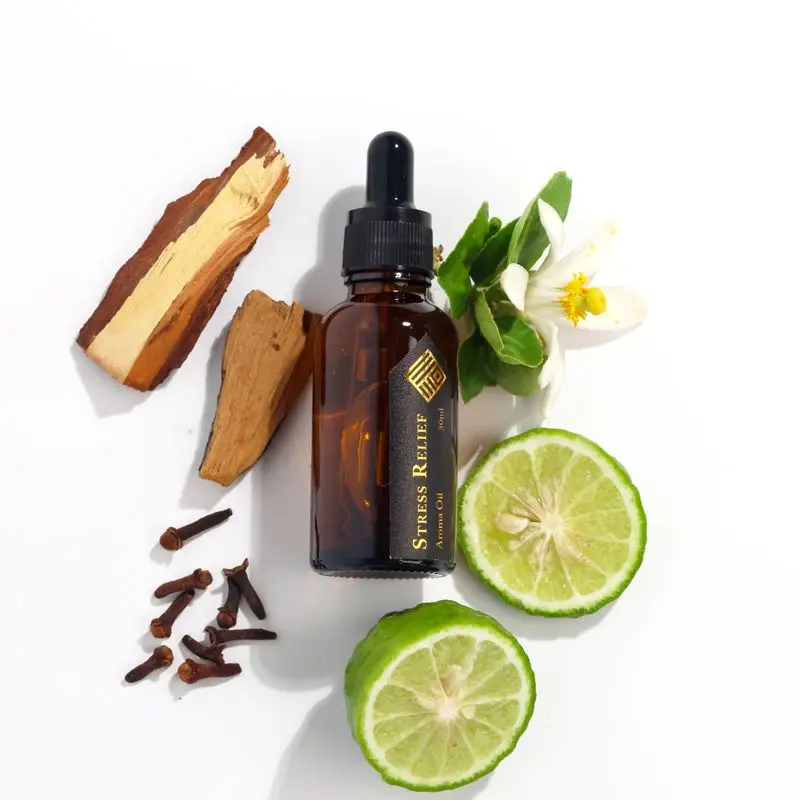 A dropper bottle of aroma oil next to citrus and cloves