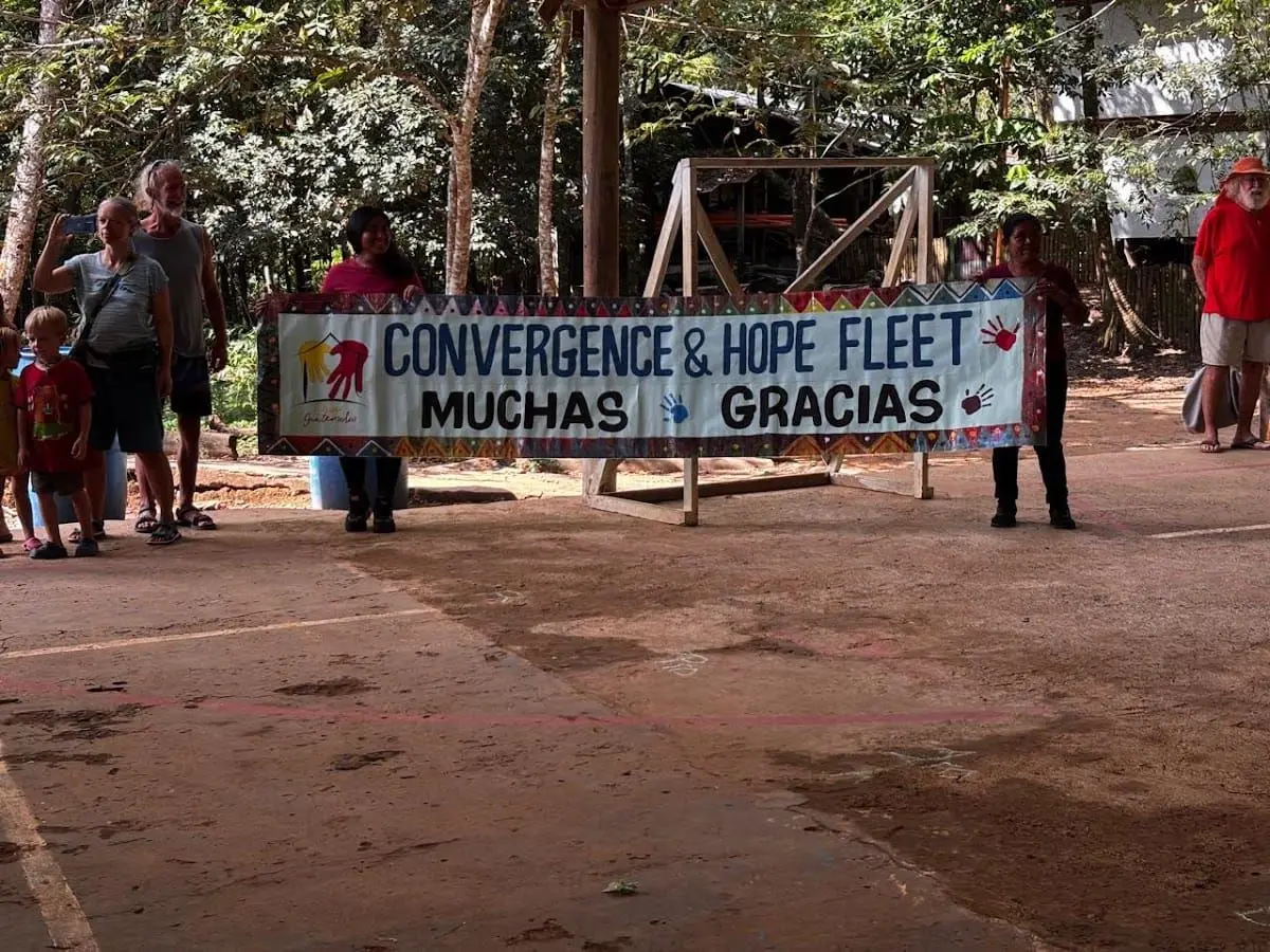 Community members thanking the Convergence & Hope Fleet with a hand-painted banner after a humanitarian aid mission