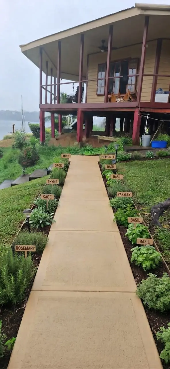 Simulation of a garden pathway beside the waterfront bungalow, with labeled beds of rosemary, sage, thyme, basil, parsley, and mint planned along the walk