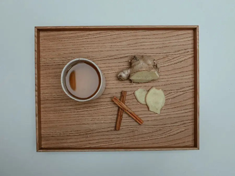 A mug of ginger tea with sliced fresh ginger and cinnamon sticks