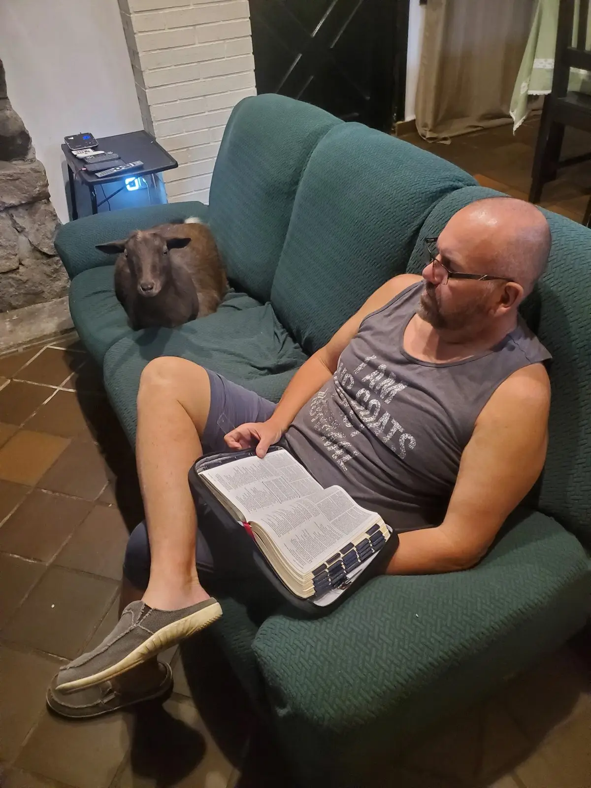 Kat curled up on the couch next to Mark while he reads his Bible
